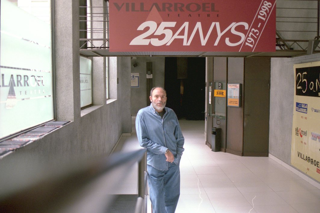 Ángel Alonso camina pel vestíbul del Villarroel Teatre sota una pancarta que diu VILLARROEL 25 ANYS 1973-1998